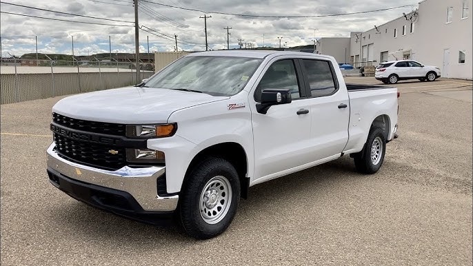 White Chevrolet Silverado crew-cab service truck parked outside the shop.