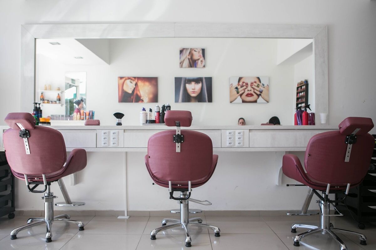 Three styling chairs facing the mirror wall