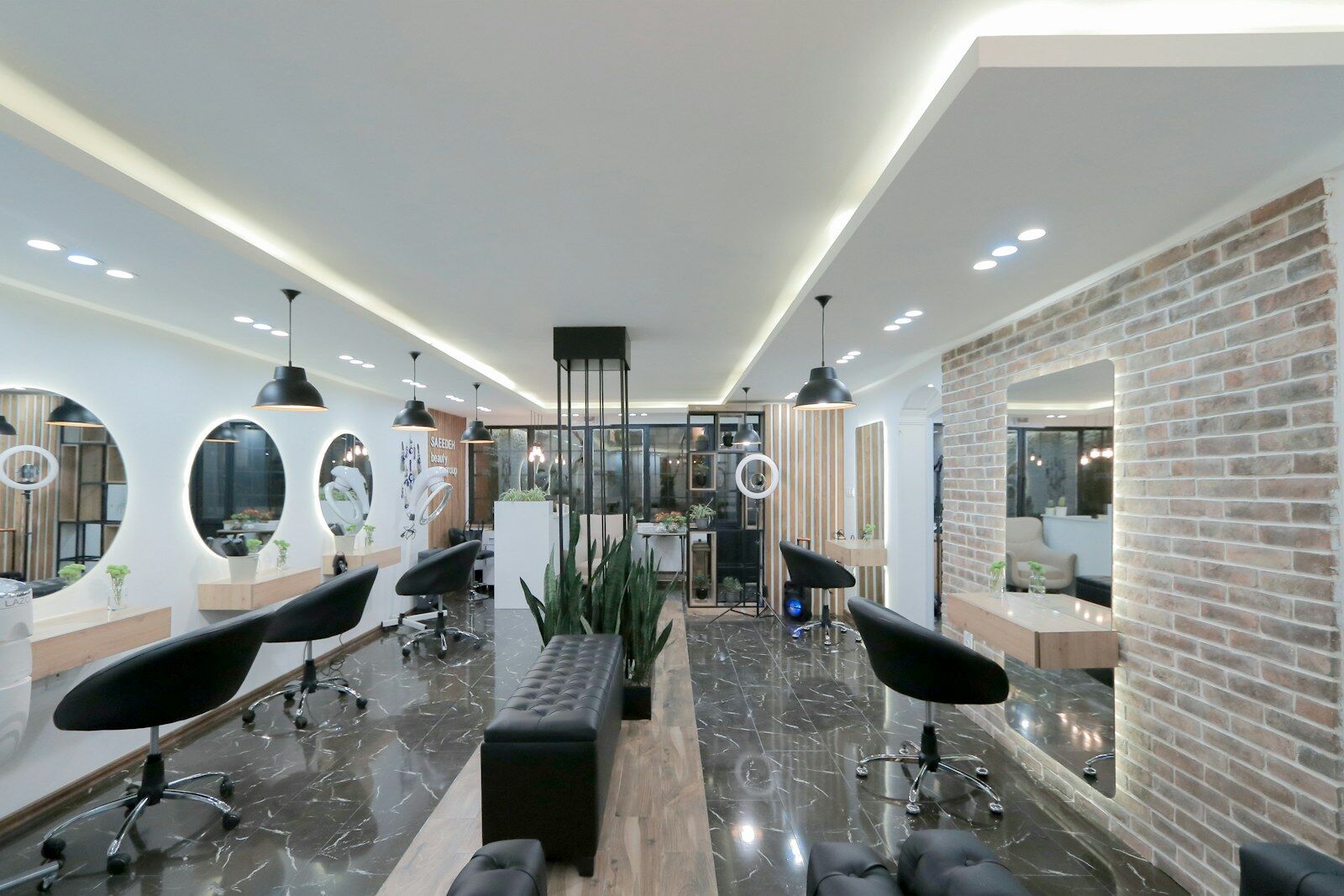 The main floor at Studio Salon: styling chairs, lit round mirrors and a brick wall