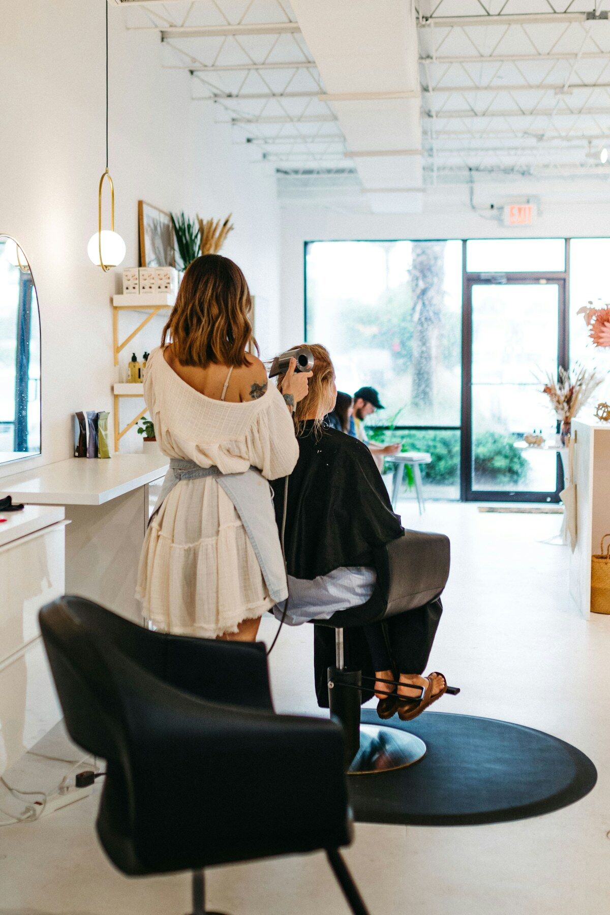 A stylist at work in the bright front window of the salon